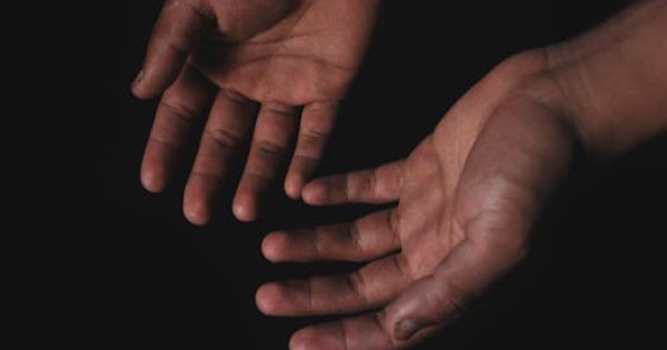 Close-up image of two hands with palms open against a black background, highlighting human skin texture.