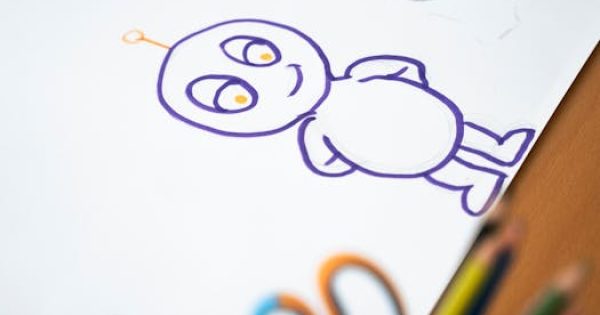 Colorful cartoon character sketch on paper with colored pencils on the side.