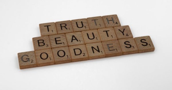 Wooden Scrabble pieces spell Truth, Beauty, Goodness on a white background.